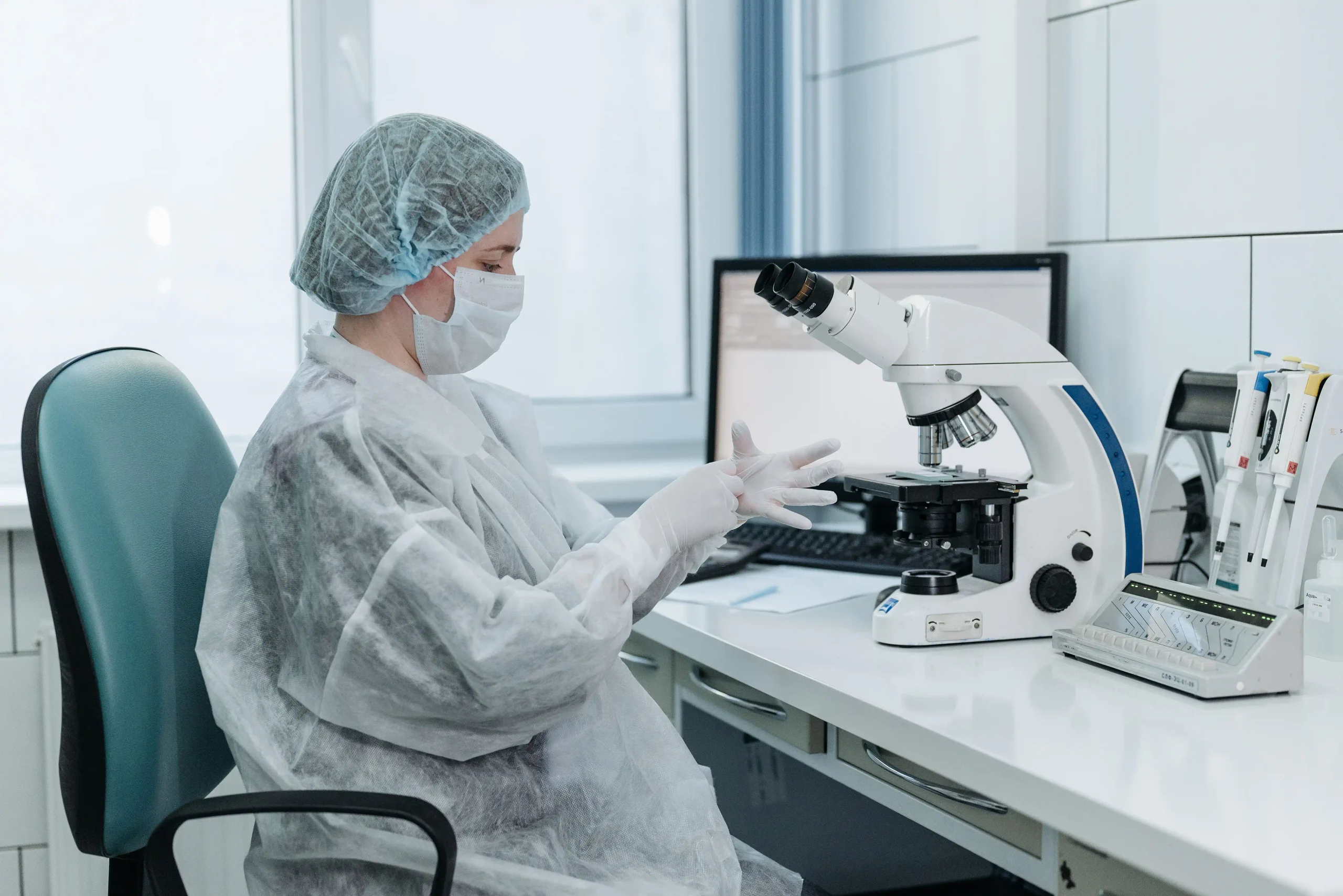 Technicienne de laboratoire en équipement de protection examinant des échantillons sous un microscope